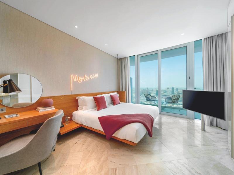 Moderne hotelkamer met twee bedden, bureau en groot raam met zeezicht.