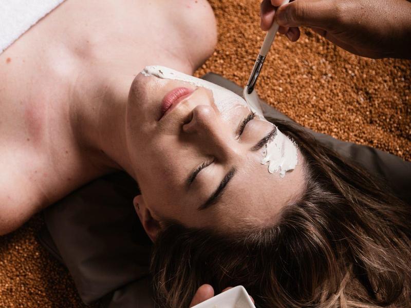 Vrouw ontspant terwijl haar wenkbrauwen in een spa worden gevormd.