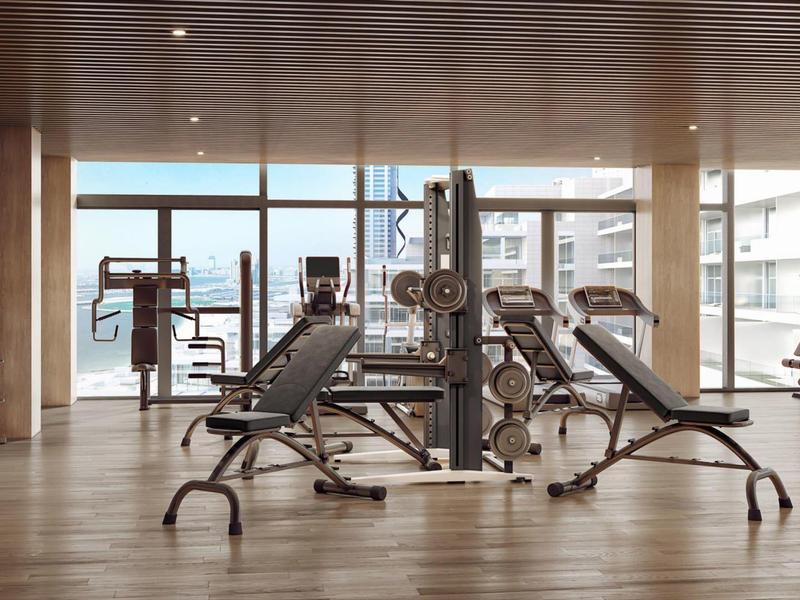 Modern gym with equipment and city view through floor-to-ceiling windows.