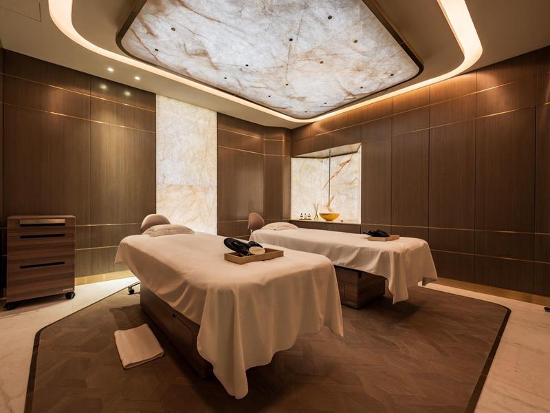 Elegant spa room with two massage tables and soft lighting.