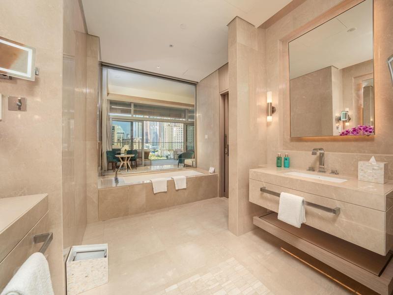 Bright bathroom with marble floors, bathtub in front of window and large mirror above sink.