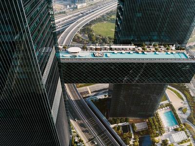 Hotel con piscina suspendida entre dos rascacielos sobre una carretera.