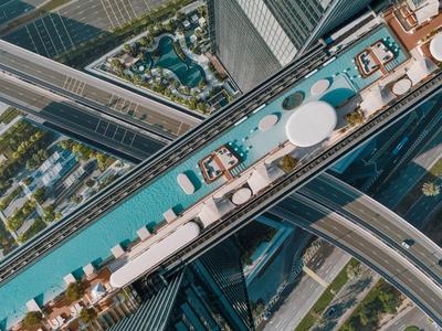 Vista aérea de una piscina larga sobre una carretera entre edificios altos en una ciudad