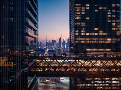 View between modern skyscrapers of a city at sunset with illuminated streets.