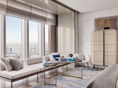 Bright hotel room with seating area, table, large window, and city view.