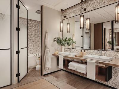 Modern bathroom with large mirror, double sink, and separate toilet.