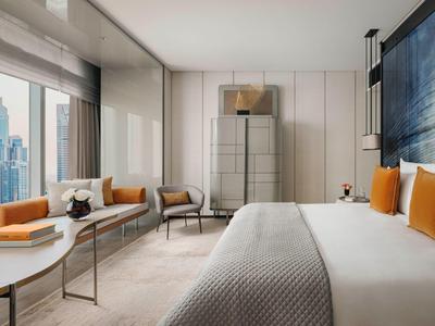 Modern hotel room with large bed, big window, and city view.