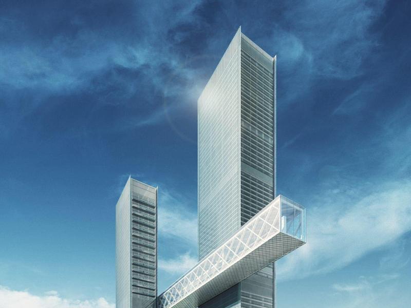 Modern high-rise building with glass skybridge against blue sky.