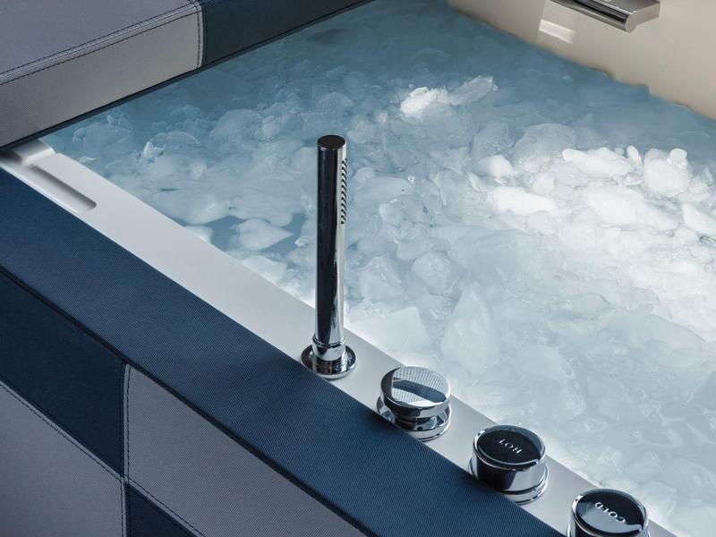 Modern hot tub with bubbling water and control knobs on the edge.