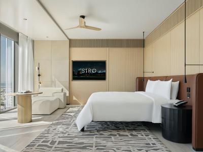 Modernes Hotelzimmer mit großem Bett, Badewanne und TV an der Wand.