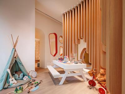 Pohodlný herní kout s herním stanem, hračkami a malým stolem v teple zařízené místnosti.