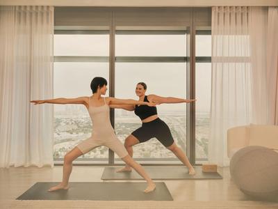 Poolbereich mit Liegestühlen und Bäumen vor einer Skyline bei klarem Himmel