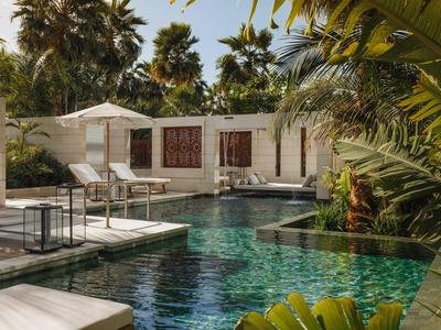 Luxuriöser Poolbereich mit Liegestühlen und tropischer Bepflanzung in einem Hotel.