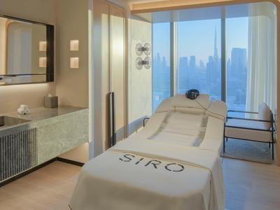 Modern spa room with massage table and large window offering city view.