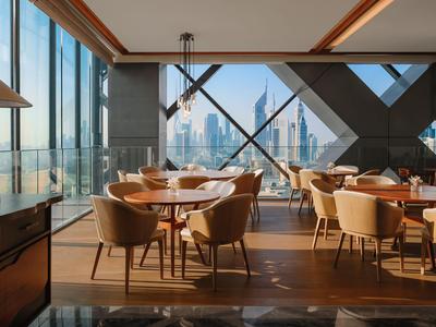 Moderní restaurace s velkými okny s výhledem na město při západu slunce.