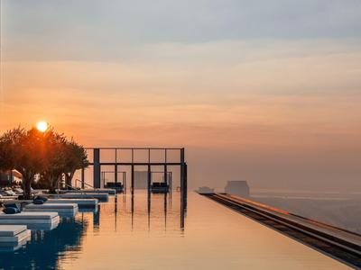 Infinity bazén s výhledem na moře při západu slunce a odpočinkovými zónami.