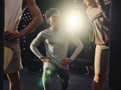 Drei sportliche Personen in Trainingskleidung mit beleuchtetem Hintergrund, die eine Pose einnehmen.