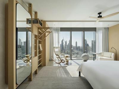 Modern hotel room with large mirror, fitness equipment, and panoramic city view.