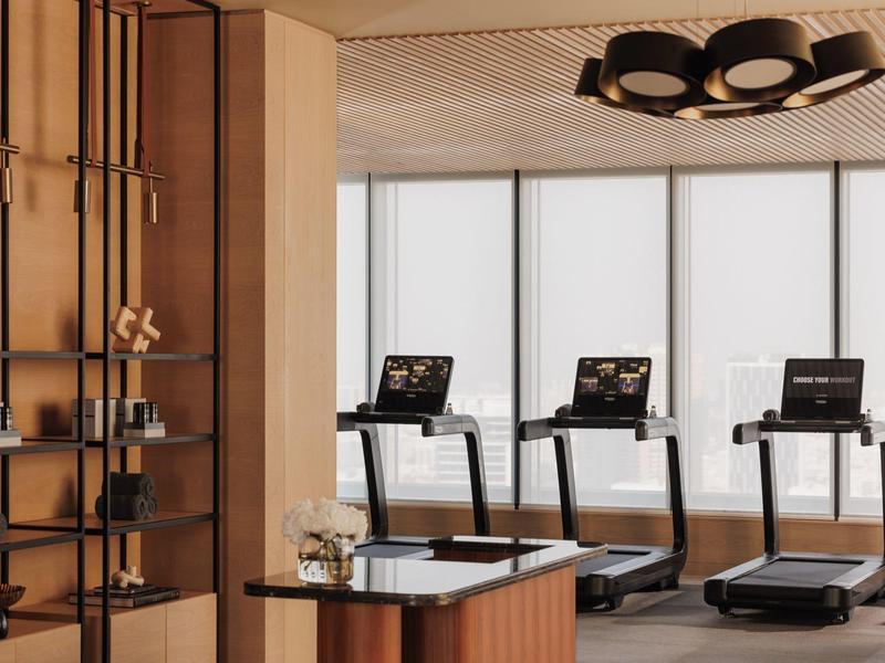 Modern gym with three treadmills in front of large windows in a hotel.