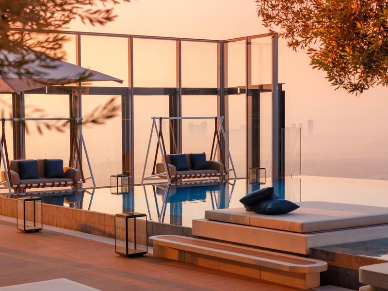 Modern outdoor area with hanging swings and cozy cushions in warm lighting.