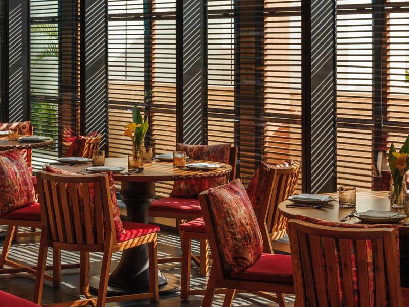 Cozy hotel dining area with wooden furniture and view through window blinds.