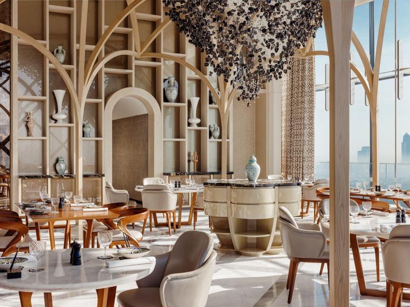 Bright, elegant restaurant with modern furniture, large windows, and artistic ceiling installation.