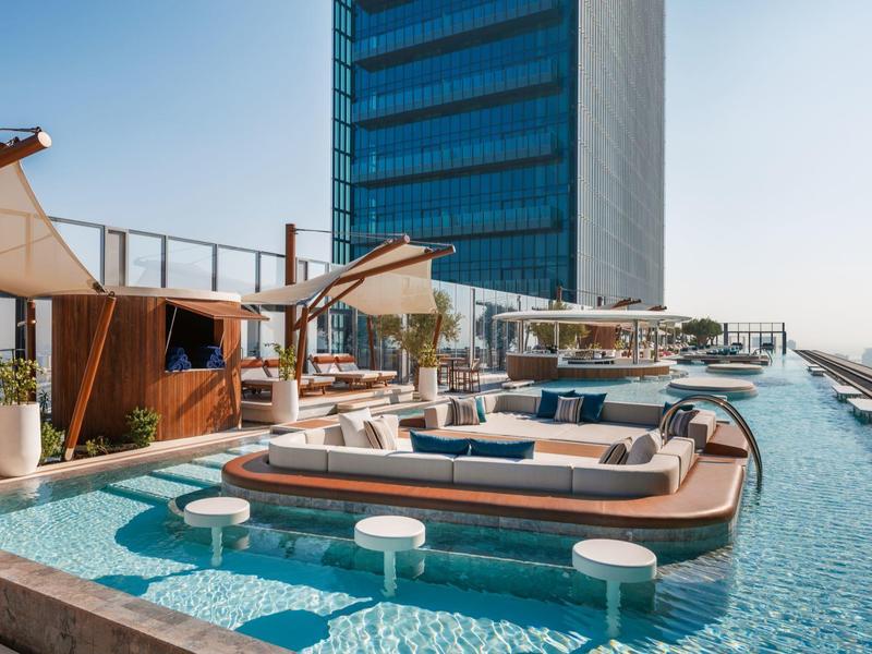 Modern hotel with rooftop terrace, pool, and cozy lounge areas with water views.