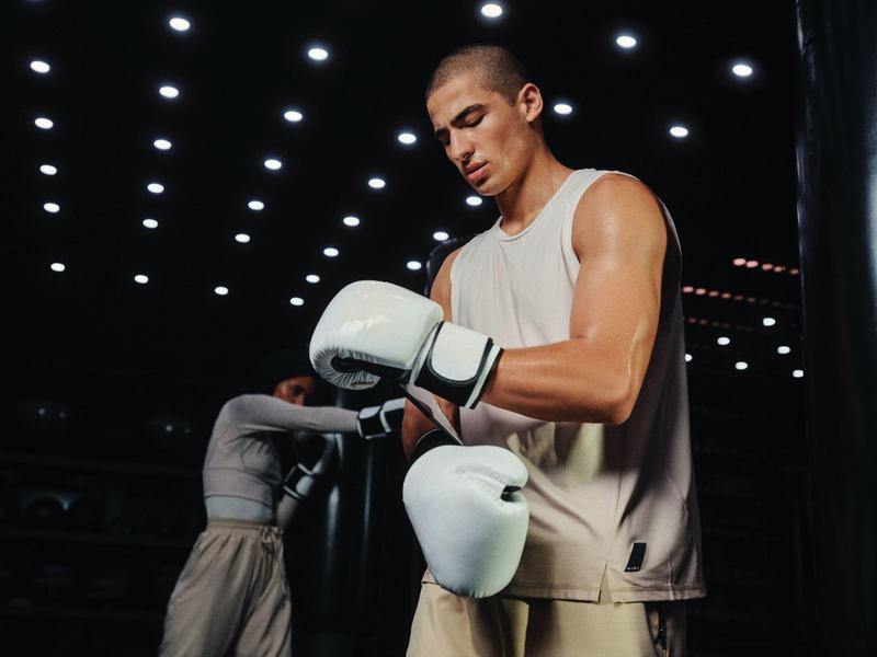 Man wearing white boxing gloves in a hall with ceiling lights