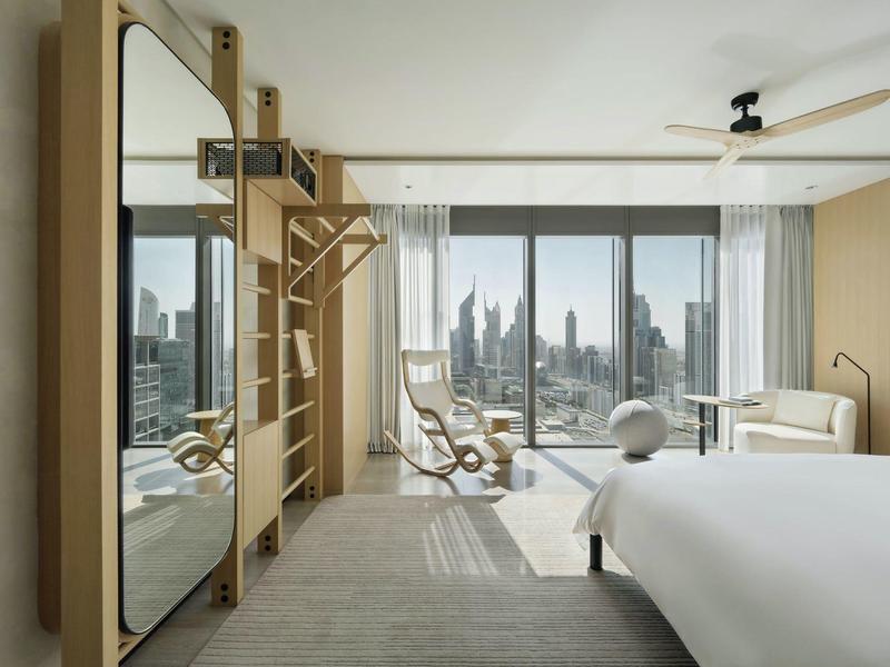 Modern hotel room with large mirror, fitness equipment, and panoramic city view.