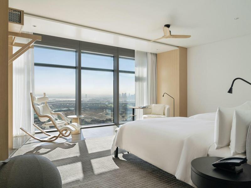 Modern hotel room with large window and balcony view of the city.