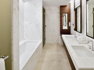 Modernes Bad mit weißer Badewanne, Doppelwaschbecken und großem Spiegel in hellem Design.