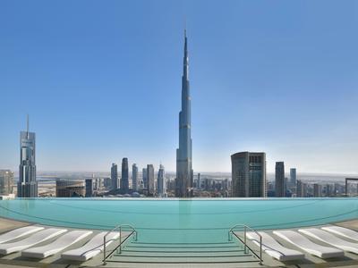Piscine à débordement avec vue sur la skyline de Dubaï et le Burj Khalifa sous un ciel clair.