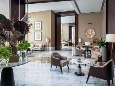 Espace lounge d'hôtel élégant avec des chaises modernes, des tables et une décoration raffinée.