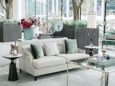 Salon moderne avec canapé, coussins verts et tables en verre dans une chambre d'hôtel près de la fenêtre.