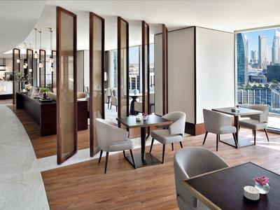 Modernes Café mit Holzboden, eleganten Sesseln und großen Fenstern mit Stadtblick.