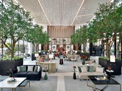 Großer, heller Innenraum mit modernen Sitzbereichen, vielen grünen Bäumen und beleuchtetem Deckendach.