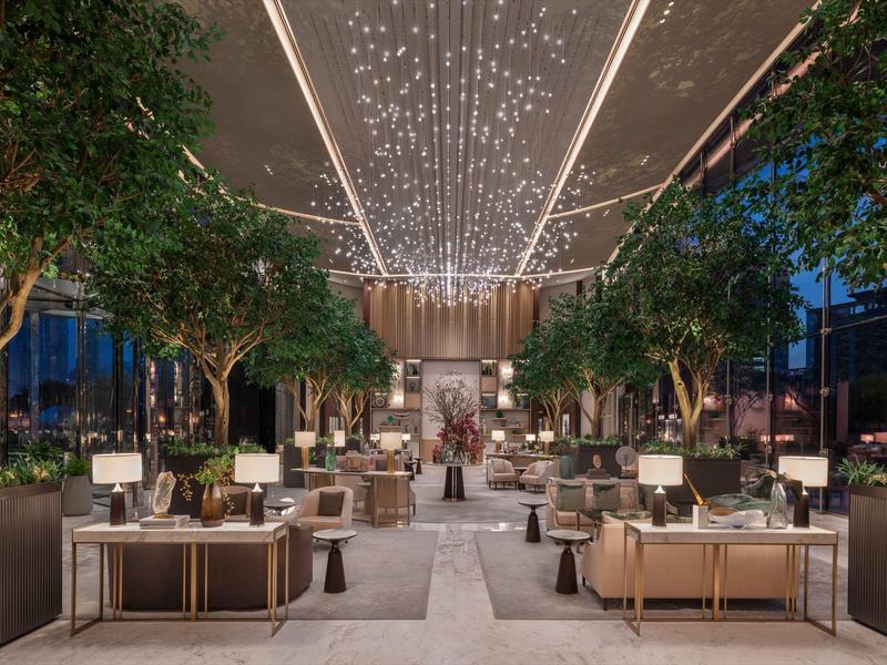 Heller, moderner Wohnraum mit bequemen Stühlen, runden Tischen und dekorativen Blumenarrangements.