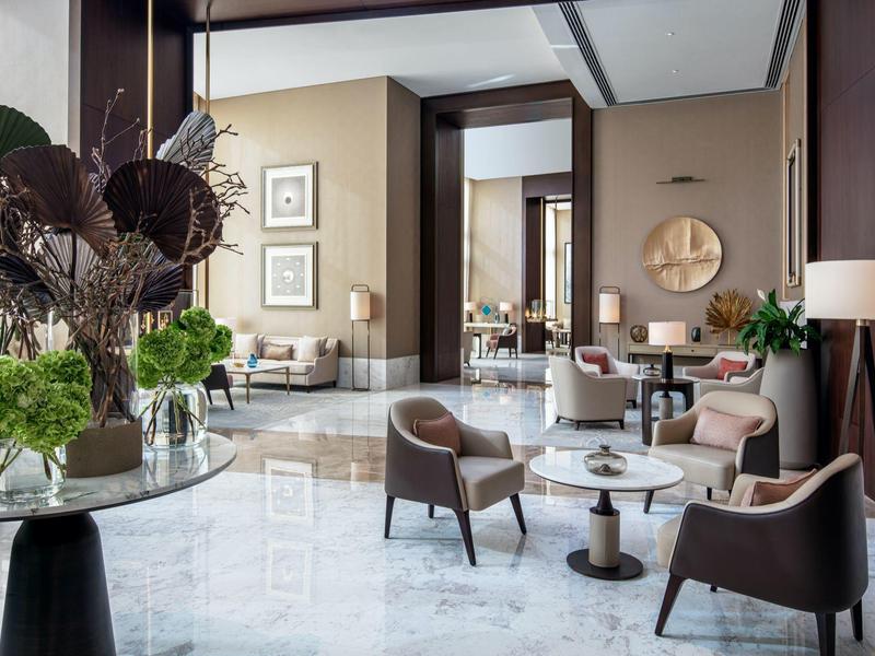 Heller, moderner Wohnraum mit bequemen Stühlen, runden Tischen und dekorativen Blumenarrangements.