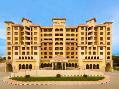 Großes, gelbes Hotel mit mehreren Etagen und symmetrischer Fassade unter blauem Himmel.