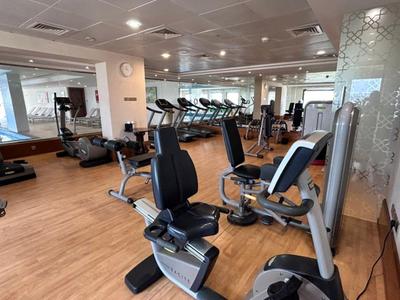 Moderner Fitnessraum mit verschiedenen Trainingsgeräten und Holzboden.