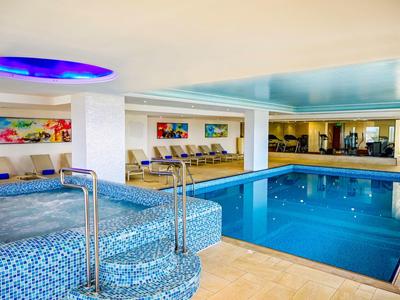 Blick auf einen modernen Innenpool mit Mosaikfliesen und Sitzbereich im Hotel.