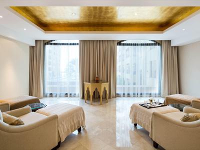 Modernes Hotelzimmer mit goldener Decke, bequemen Betten und großen Fenstern mit Vorhängen.