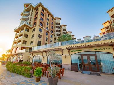 Großes Hotelgebäude mit Terrasse und Sitzgelegenheiten bei Sonnenuntergang.
