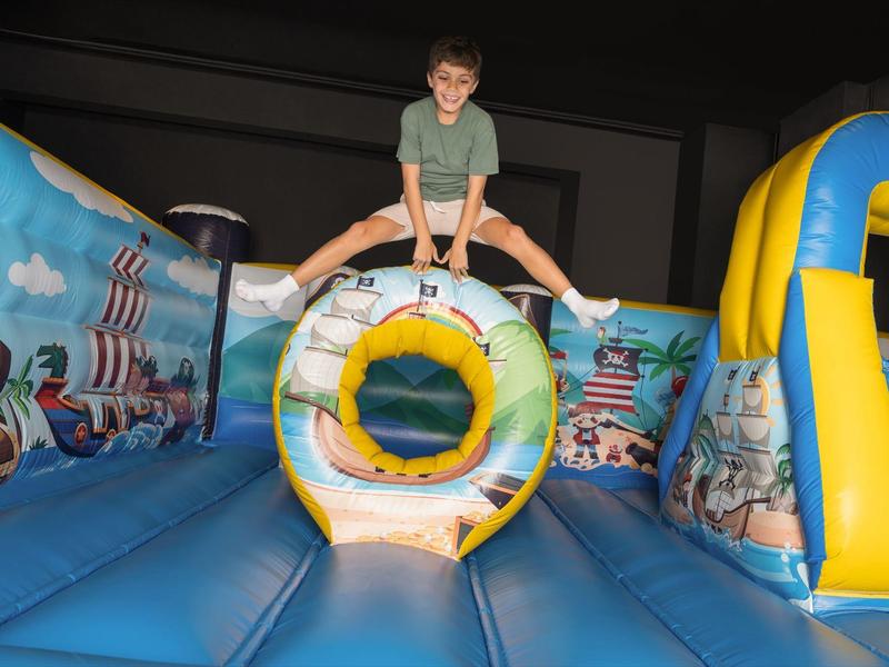 Kind springt auf einer aufblasbaren Hüpfburg mit Piratendesign.