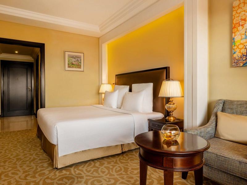 Gemütliches Hotelzimmer mit Doppelbett, Nachttischlampen und einem Sitzbereich mit Sofa.