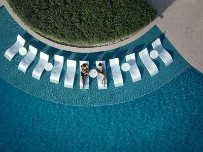 Overview of pool with built-in loungers and two people relaxing.