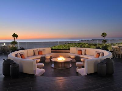 Grand espace circulaire avec foyer sur terrasse au coucher du soleil avec vue sur la mer.
