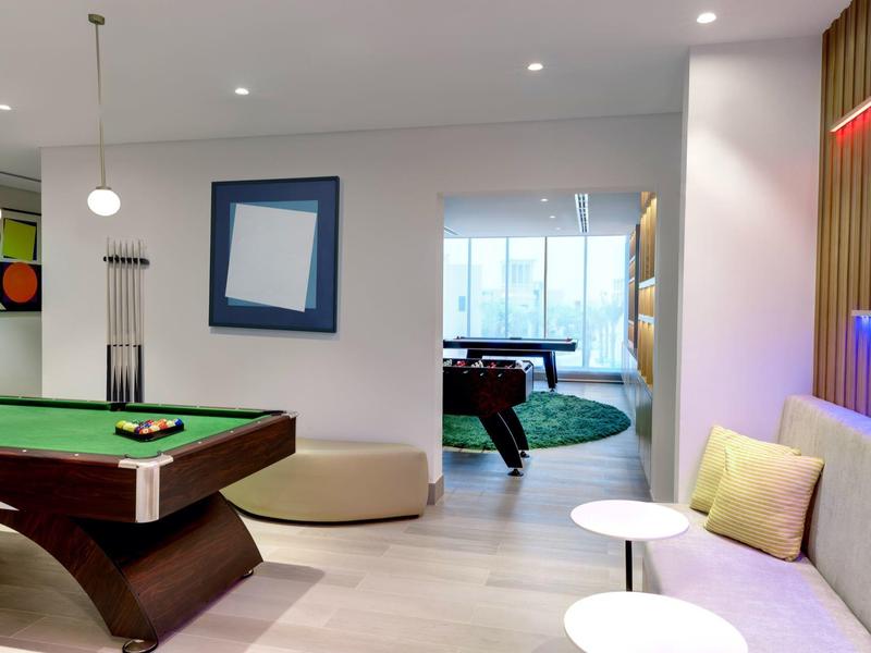 Salle de loisirs moderne avec tables de billard, banquette confortable et éclairage élégant.