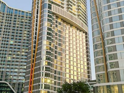 Hohe moderne Glasfassaden von Wolkenkratzern mit grünem Vorbau und umliegenden Pflanzen.