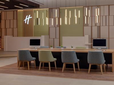 Moderner Konferenztisch mit bunten Stühlen und schwebenden Pendelleuchten in hellem Büroraum.